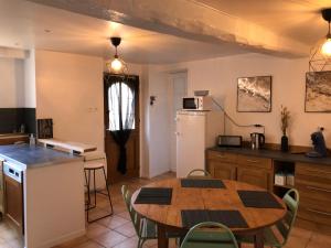 a kitchen and dining room with a table and a refrigerator at le refuge de Majèle 