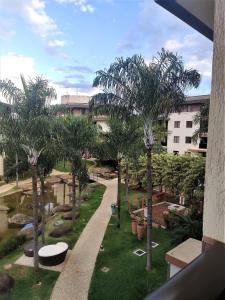 vistas a un jardín con palmeras y a un edificio en L316 LA Apartamento aconchegante resort à beira lago, en Brasilia