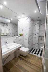 ein weißes Bad mit einem Waschbecken und einem WC in der Unterkunft Korca Luxury Apartments & Rooms in Korçë
