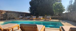 una piscina con tumbonas y una mesa en Masseria Violante Boutique Hotel, en Ruffano