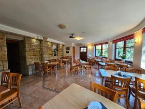 a restaurant with wooden tables and chairs and windows at Villa Alexandra in Polanica-Zdrój