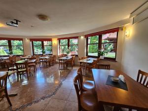 a restaurant with wooden tables and chairs and windows at Villa Alexandra in Polanica-Zdrój