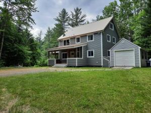 a gray house with a garage on a yard at 157SL peaceful forest retreat in Franconia