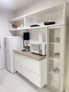 Il comprend une cuisine blanche équipée d'un four micro-ondes et d'un réfrigérateur. dans l'établissement V1502 Apart área central com vista para esplanada, à Brasilia