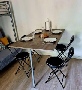 una mesa de madera con sillas y platos. en Superbe Studio en plein cœur de Luchon en Luchon