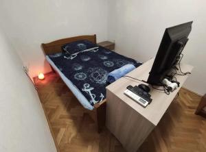 a bedroom with a bed and a desk with a television at Aretha apartman i sobe in Novi Vinodolski