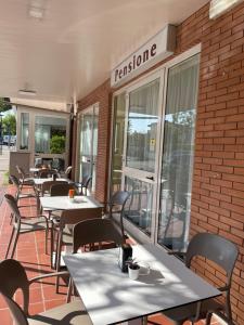 - une rangée de tables et de chaises à l'extérieur d'un restaurant dans l'établissement Pensione Ornella, à Lignano Sabbiadoro