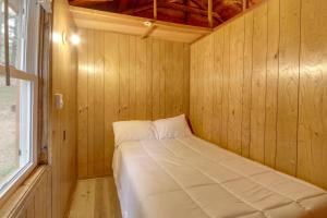 Bett in einem Holzzimmer mit Fenster in der Unterkunft Waterfront Lake Cabin Close to Boating and Fishing! in Lake