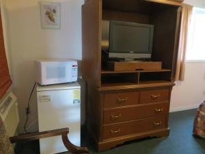 um quarto com uma televisão, um frigorífico e um micro-ondas em Villa Nova Motel em Wasaga Beach