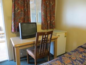 um quarto com uma secretária, uma televisão e uma cadeira em Villa Nova Motel em Wasaga Beach