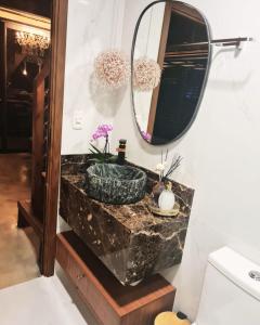 y baño con lavabo de mármol y espejo. en Cabanas Bougainville Hospedagem sofisticada em nova Petrópolis en Nova Petrópolis