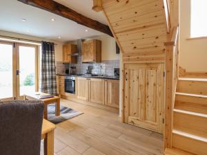a large kitchen with wooden cabinets and a staircase at Old Cart House in Oswestry