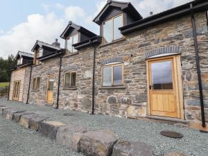 a stone house with wooden doors and windows at Llety Dewi in Oswestry