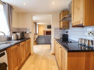a kitchen with wooden cabinets and black counter tops at Llety Dewi in Oswestry
