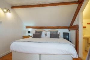 um quarto com uma grande cama branca num quarto em Thomas Carlyle Cottage em Thornhill