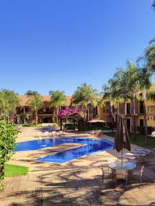 - une piscine avec des tables, des chaises et des palmiers dans l'établissement Imperial Palace Hotel Sorriso, à Sorriso