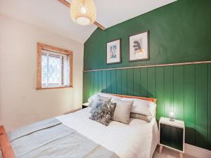 a bedroom with a green accent wall and a bed at Weavers Cottage in Barrowford