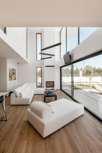 uma sala de estar com mobiliário branco e janelas grandes em Sunshine Villa em Nafplio