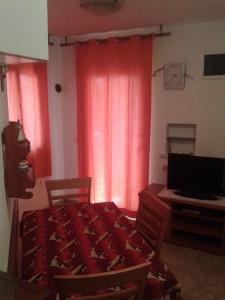 Cette chambre comprend une table, un bureau et des rideaux rouges. dans l'établissement Apartments Belvedere - A2, à Nečujam