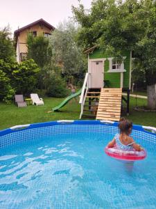 Ein kleines Mädchen reitet auf einem Schlauch im Pool in der Unterkunft Casa Bunicii Comarnic in Comarnic