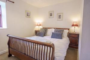 a bedroom with a bed with two lamps on a table at Drumlanrig Cottage in Thornhill