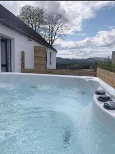 a swimming pool with blue water in front of a house at Drumlanrig Cottage in Thornhill