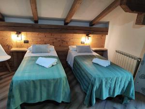 two beds in a room with wooden walls at A casa da Elide in Aymavilles