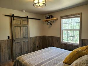 een slaapkamer met een bed, een raam en een deur bij Laurel Haven a Modern Cabin Retreat near Gatlinburg in Cosby