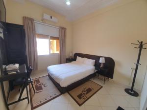 a bedroom with a large bed and a window at Hotel Achark in Bou Arfa