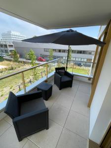 a balcony with two chairs and an umbrella at Superbe T2 proche de la Gare RER TGV Massy Palaiseau in Massy