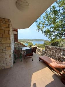 eine Terrasse mit einem Tisch und Stühlen sowie Blick auf das Wasser in der Unterkunft Apartments Belvedere - A3 in Nečujam