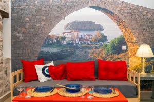 a couch with red pillows and a wall with a mural at Ydor apartment in Hydra