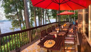 a row of wooden tables with umbrellas on a deck at Algonquin Island 'Luxe' Cottage at the edge of the Park in South River