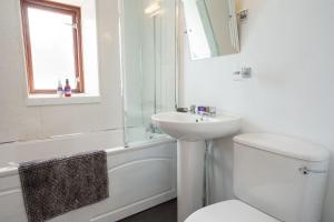 a white bathroom with a toilet and a sink at Morton Cottage in Thornhill