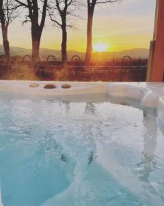 a large swimming pool with a sunset in the background at Dalgarnock Cottage in Thornhill