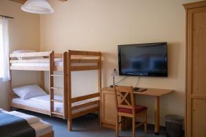 a room with bunk beds and a desk and a television at BurgenLandhaus in Gols