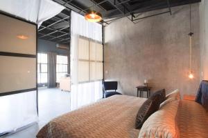 a bedroom with a large bed and a chair at Brand New Gorgeous Industrial Loft in Downtown Ens in Ensenada
