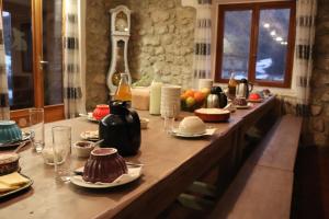een lange houten tafel met eten en drinken erop bij La Grangerie in Aillon-le-Jeune