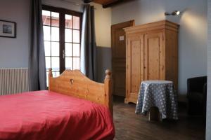 um quarto com uma cama vermelha e um armário de madeira em La Grangerie em Aillon-le-Jeune