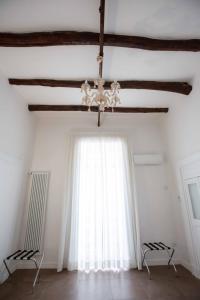 Camera bianca con lampadario pendente e finestra di Domus Delia Luxury Apartment a Napoli