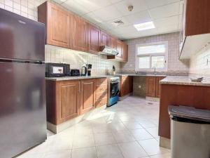 uma cozinha com armários de madeira e um frigorífico de aço inoxidável em Key View - Silicon Star no Dubai