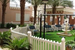 a white fence in a yard with chairs and palm trees at Key View - Silicon Star in Dubai