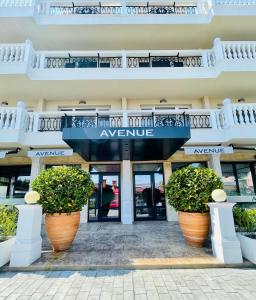 un bâtiment avec deux grands pots de plantes devant lui dans l'établissement Hotel AVENUE, à Ravda