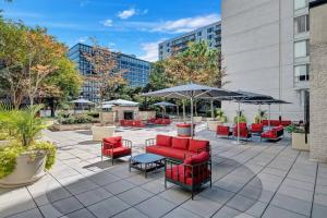 a patio with red chairs and tables and umbrellas at Amazing 2 BR Apt + Den @Crystal City With Gym in Arlington