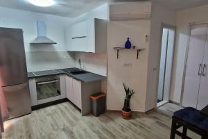 une cuisine avec des armoires blanches et une plante en pot dans l'établissement Apartments Belvedere - A4, à Nečujam