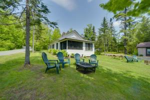 a group of chairs sitting in the grass in front of a house at Lakefront Adirondack Getaway with Beach and Kayaks! in Lake Pleasant