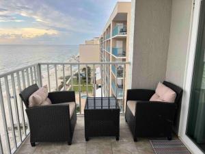 a balcony with two chairs and a view of the ocean at Ocean House 1806 in Gulf Shores +48 photos