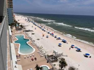a beach with many umbrellas and chairs and the ocean at Ocean House 1806 in Gulf Shores