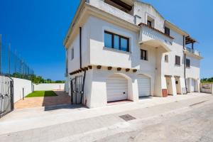 ein großes weißes Haus mit zwei Garagentüren in der Unterkunft 5 - Relax e comfort in casa con giardino - Sa Crai Apartments Sardinian Experience in Lotzorai