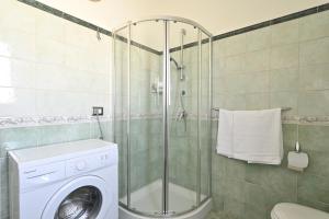 een badkamer met een douche en een wasmachine bij 5 - Relax e comfort in casa con giardino - Sa Crai Apartments Sardinian Experience in Lotzorai